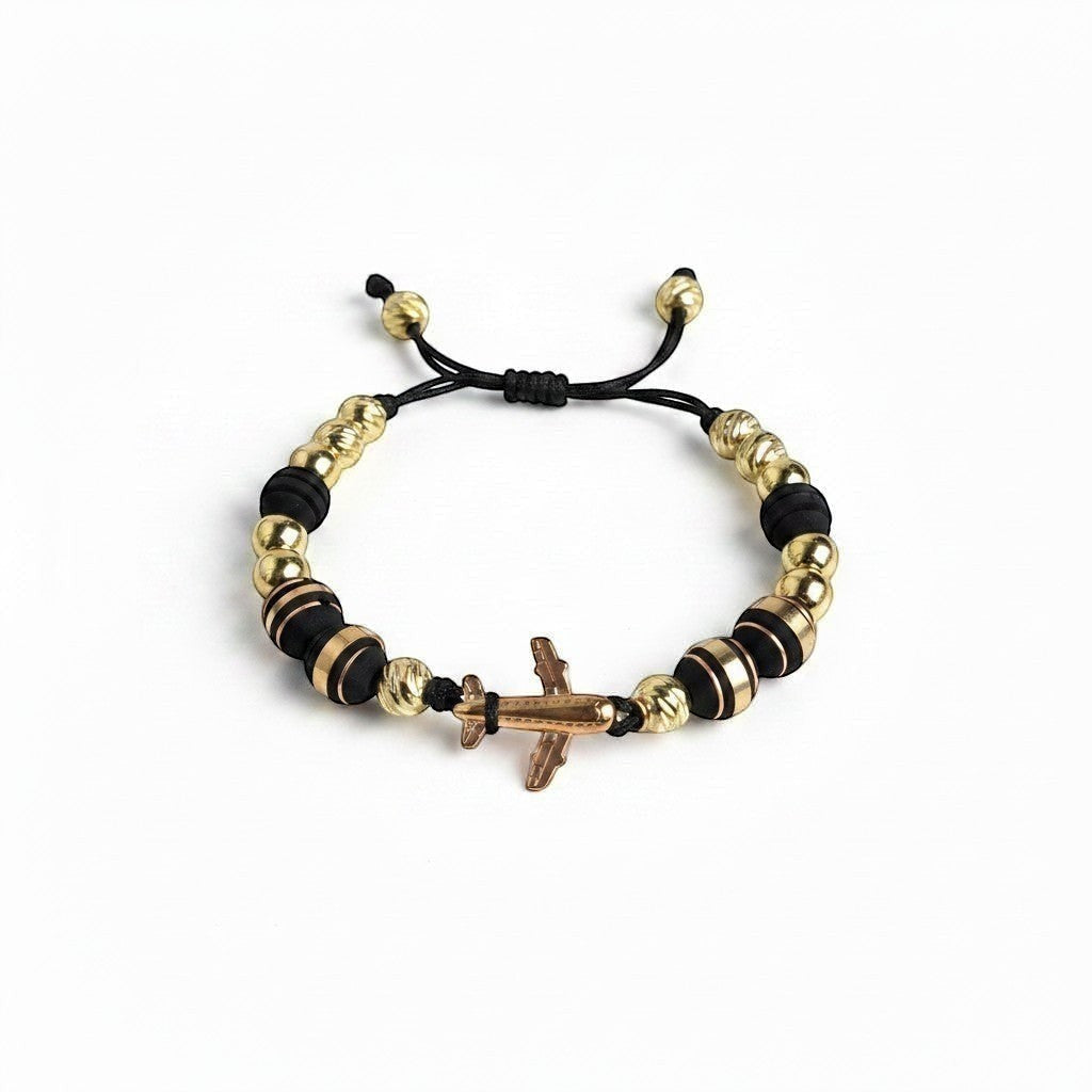 Pulsera ajustable Air Store con abalorios dorados y negros y un dije central de avión metálico para viajeros